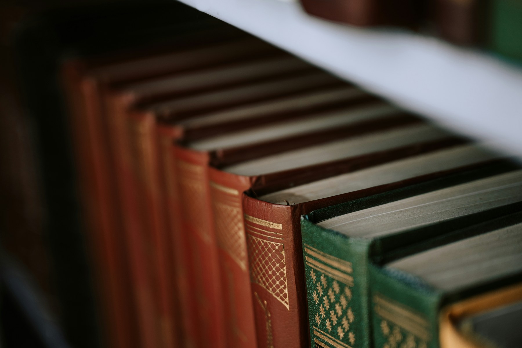 Bibliothèque ancienne sur trois étages, dos en cuir aux dorures travaillées, atmosphère feutrée — archives collectives.