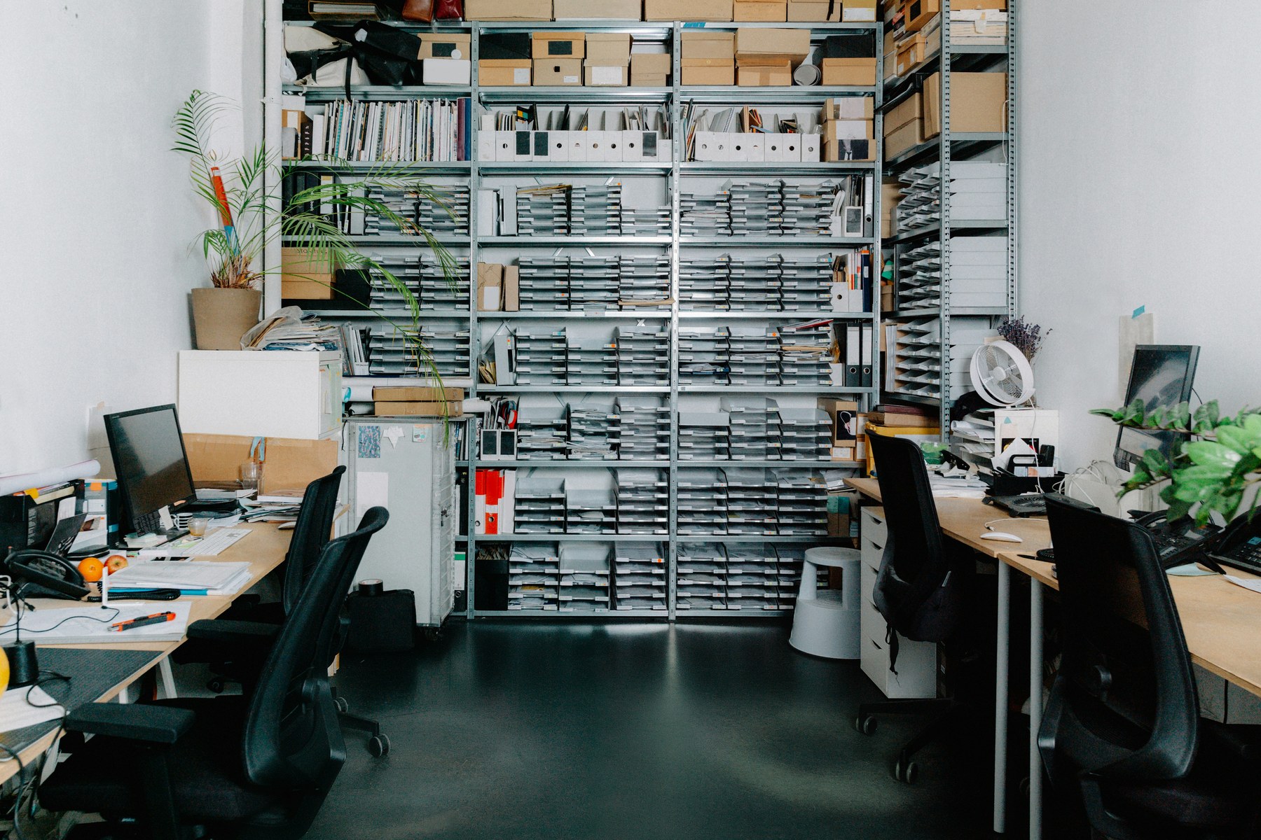 Salle de bureaux moderne avec mur d'archives en compartiments métalliques — environnement de gestion documentaire.